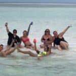 Group of guests posing together in shallow water at a Key West sandbar