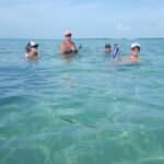 Three guests floating in clear turquoise water at a Key West sandbar